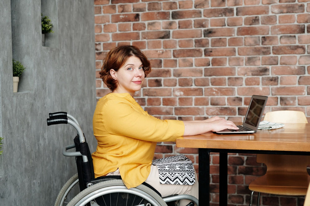 Junge Frau im Rollstuhl arbeitet am Computer