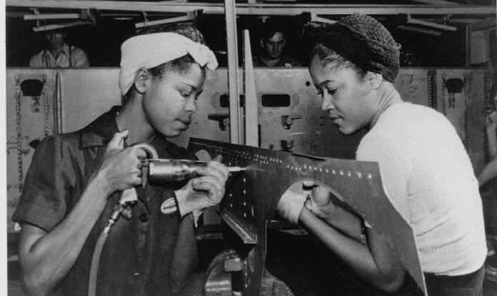 Two black women working metal parts