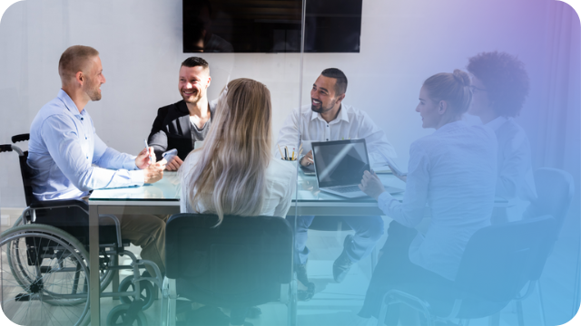 A group of business people sitting around a table, one is sitting in a wheel chair