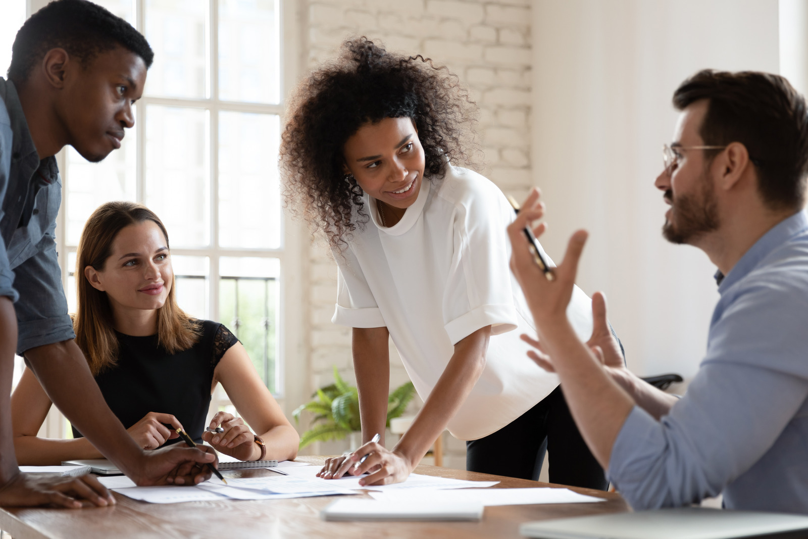 Diverse businesspeople listen team leader during meeting in boardroom